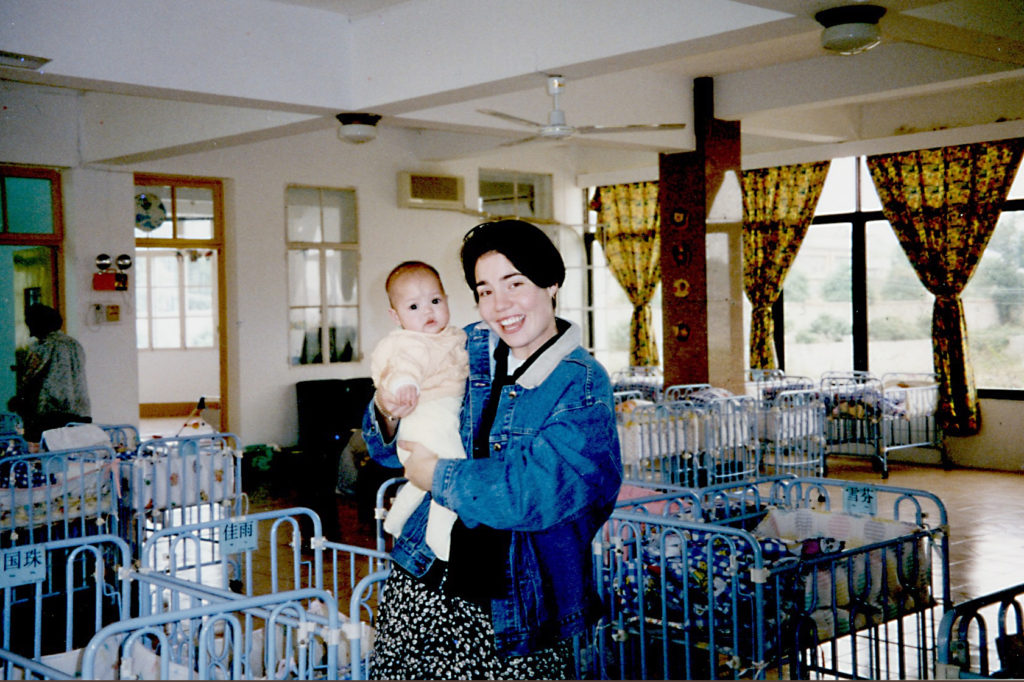 Susie Doig holding a baby at an orphanage in China in the 1990s