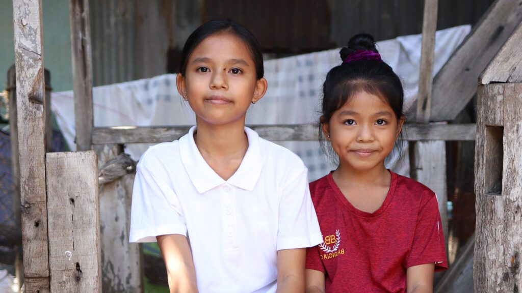 Sisters sitting on steps outside their home