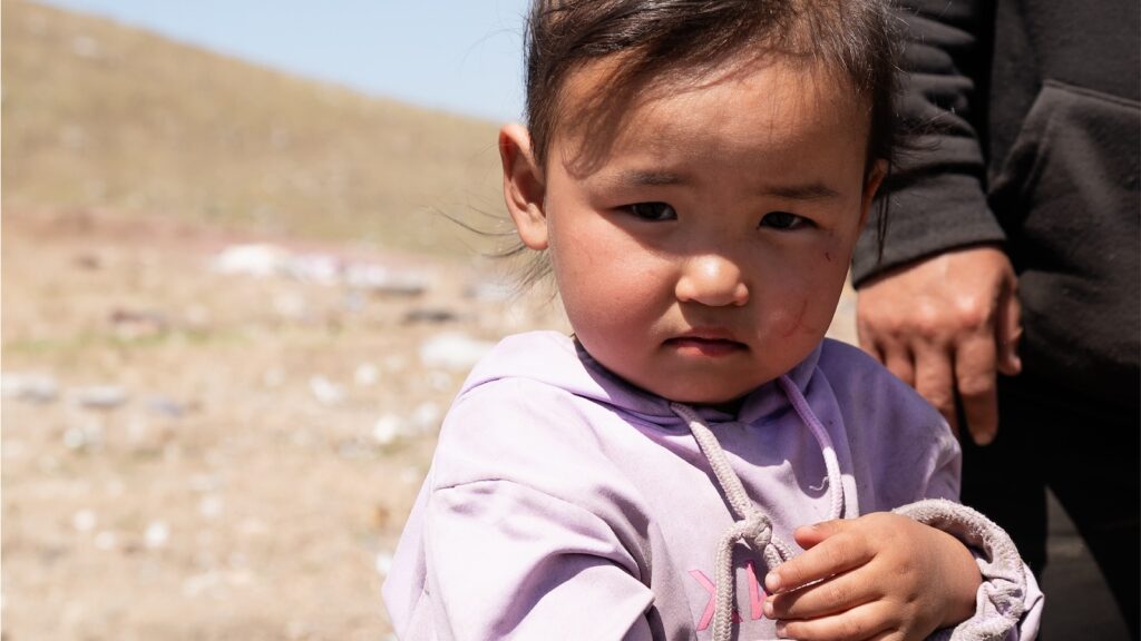 Young girl in Mongolia standing in a barren, cold landscape