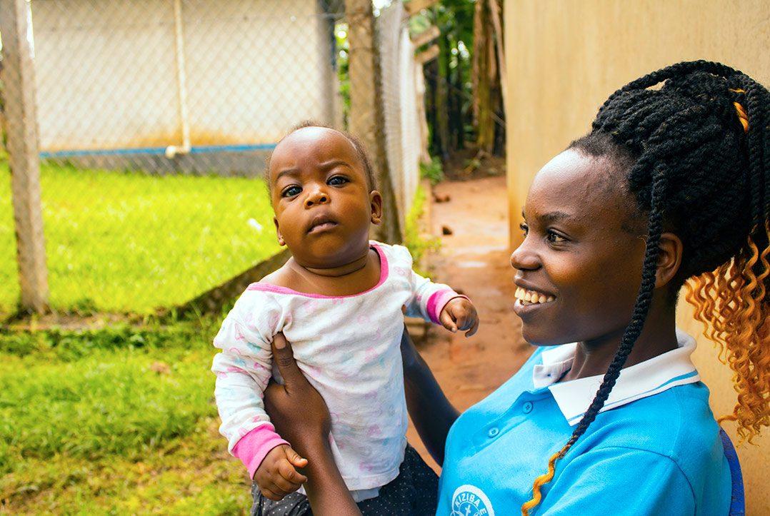 A mom in Uganda holds up her baby, smiling