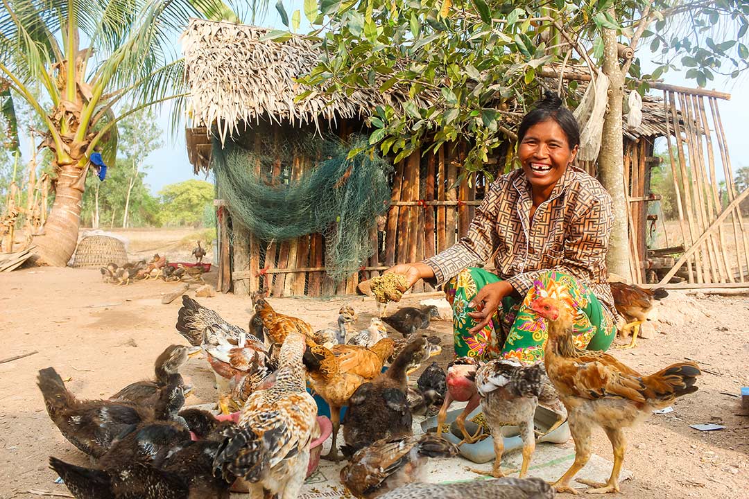 A woman laughs with her chickens