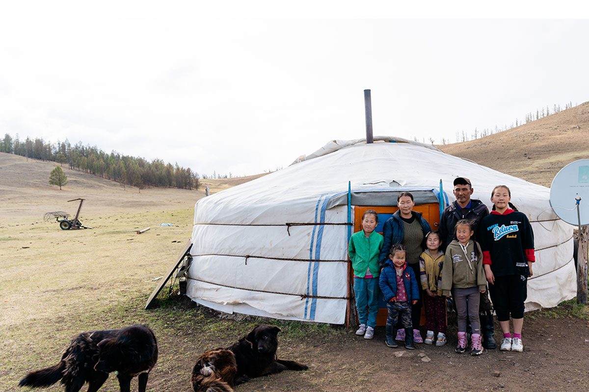 A nomadic herding family in Mongolia stands outside their ger