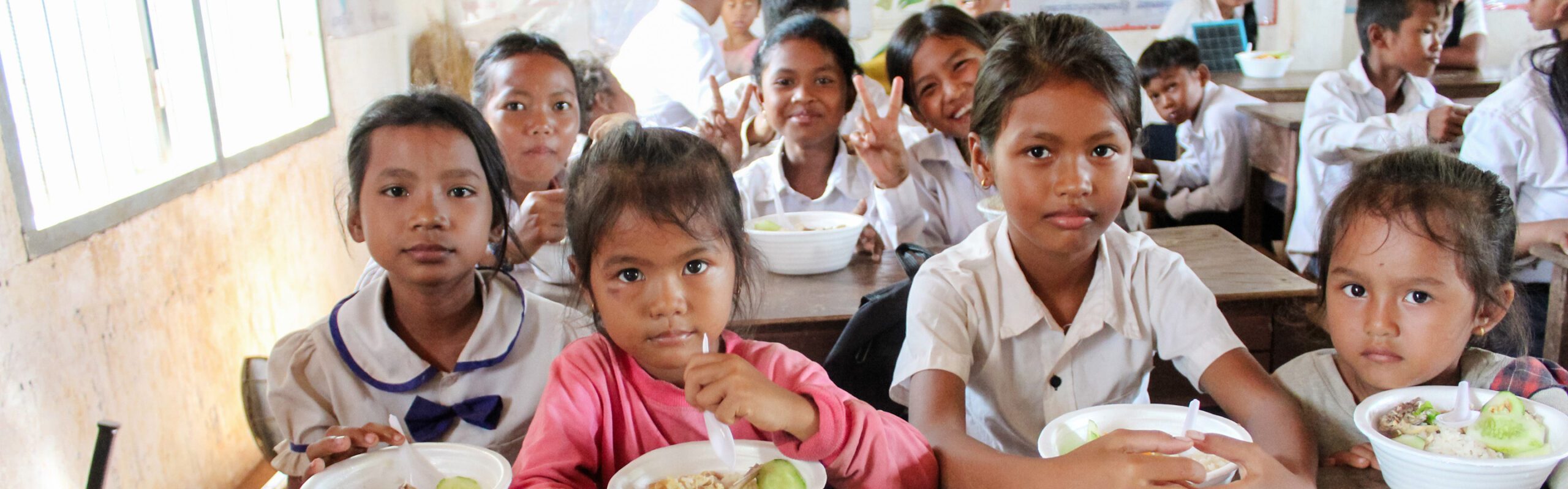 Group of children sitting in a classroom eating lunch