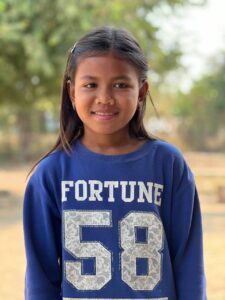 12-year-old Chaya from Cambodia wears a blue and white sweatshirt