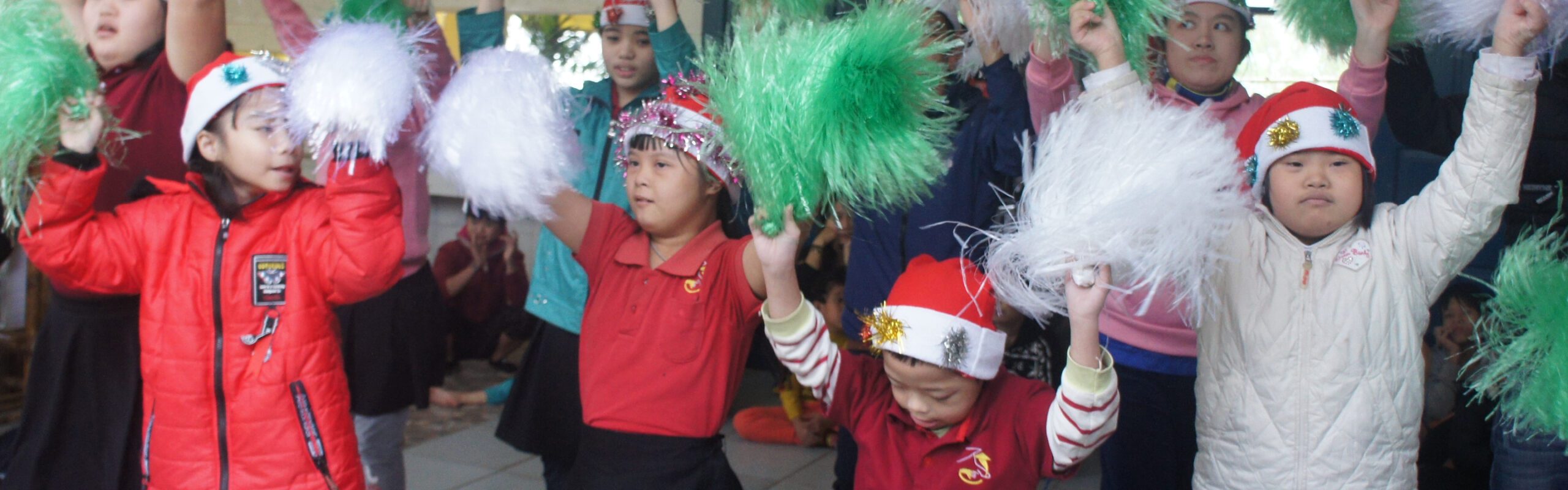 Group of children at a Christmas party holding pom poms