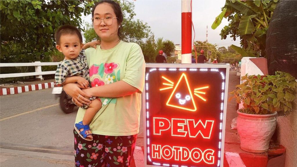 Thuong, a single mother in Vietnam, holds her child in front of her food cart