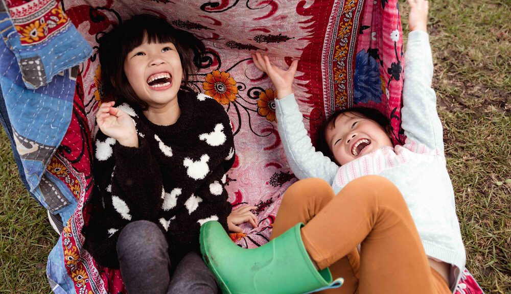 Adoptive sisters Ivy and Lili play on a blanket/