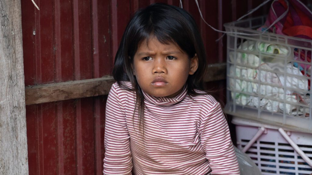 Young girl with a furrowed brow sitting in her house