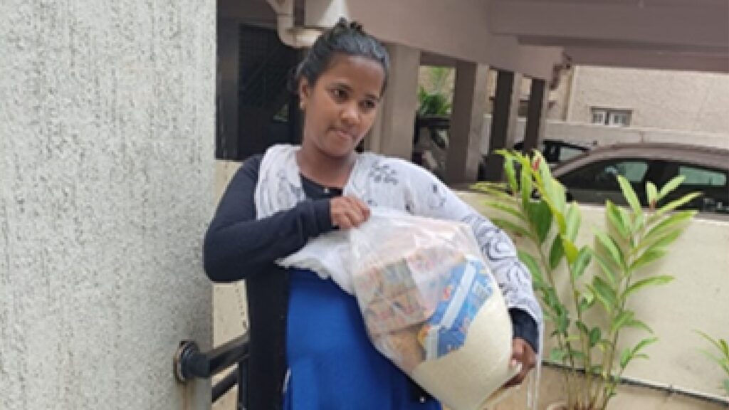 Holt sponsors and donors offer food assistance to a young mother in India, who  holds an emergency food pack 