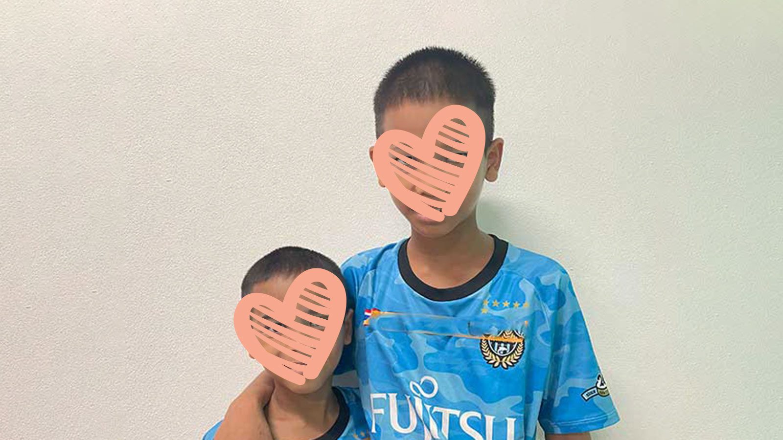 Two sibling boys in SE Asia hugging each other. Both are waiting for adoption.