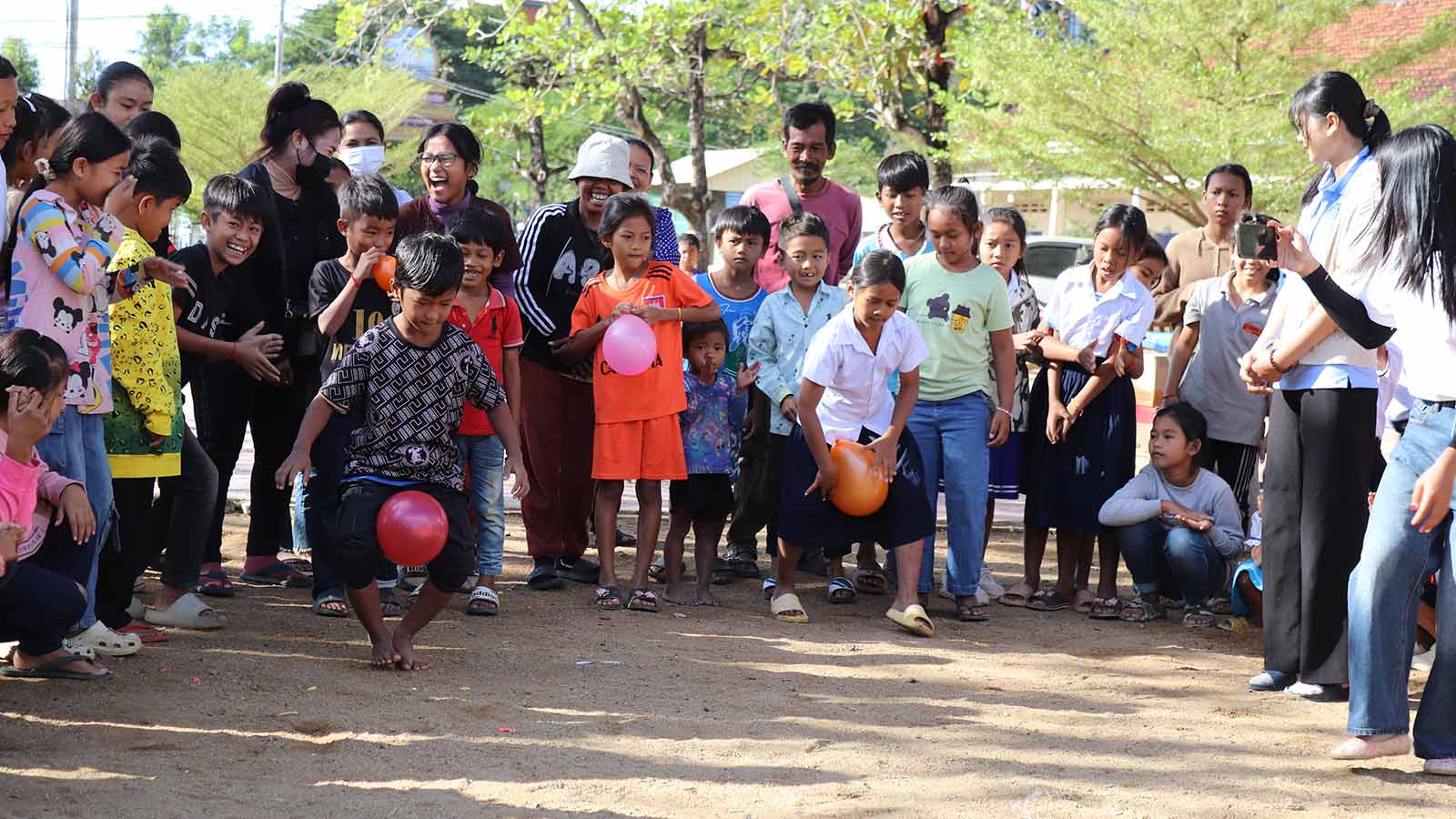 children in Cambodia celebrate the end of the year with a balloon game outdoors