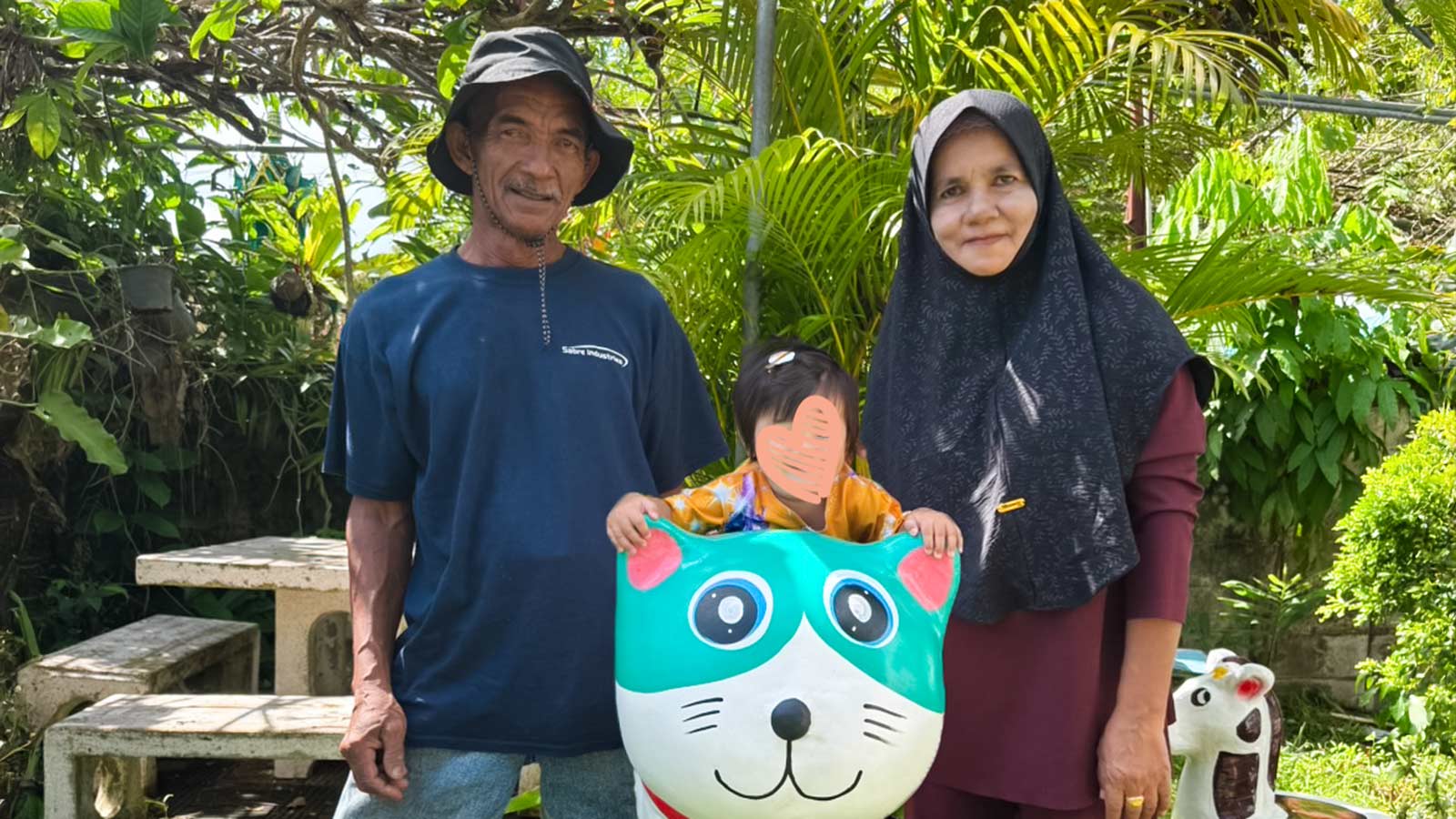 A family of three smiles in Thailand with a cute animal statue