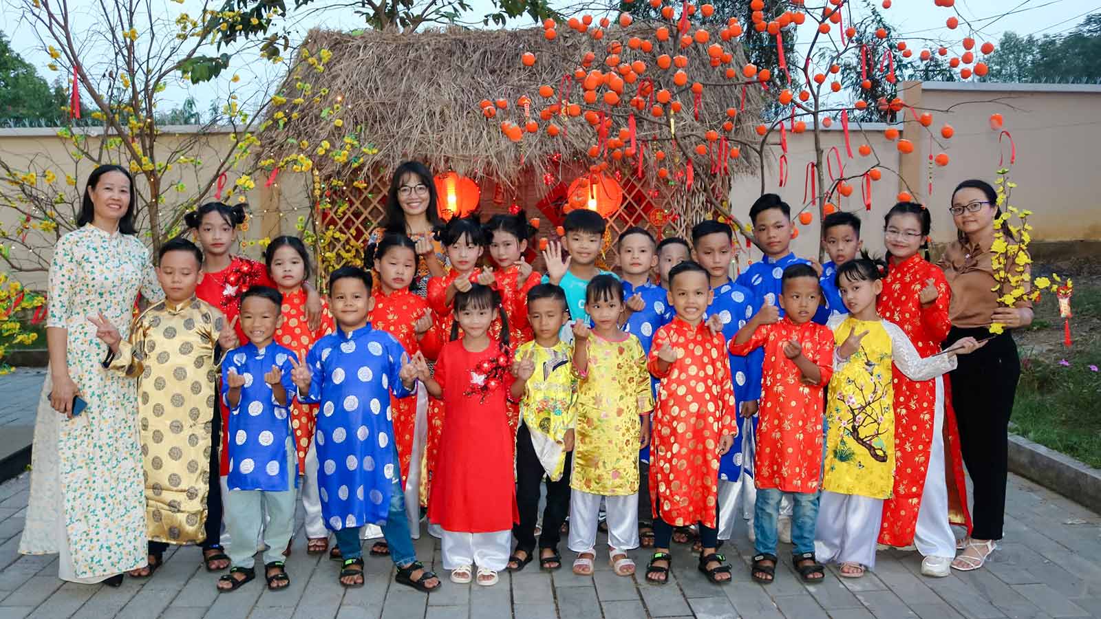 A group of children wearing traditional Vietnamese attire smile for a photo during Tet