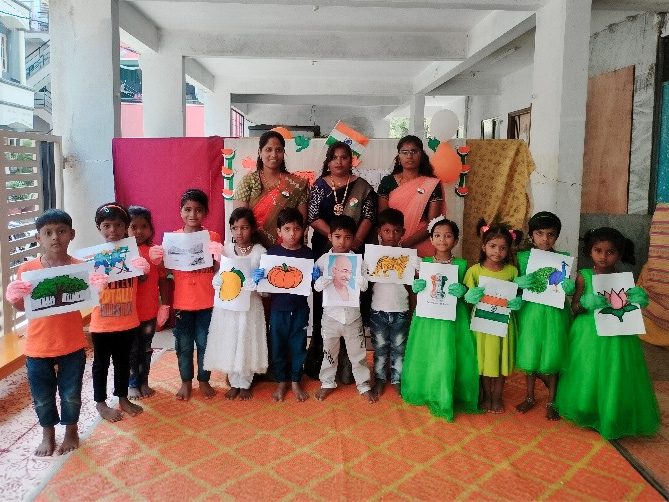 Children in India hold up their artwork in an outdoor hallway