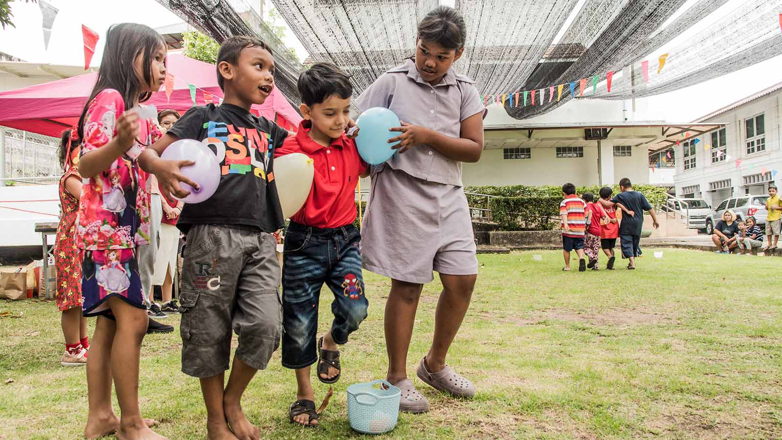 children in Thailand celebrate Christmas with a balloon game outside