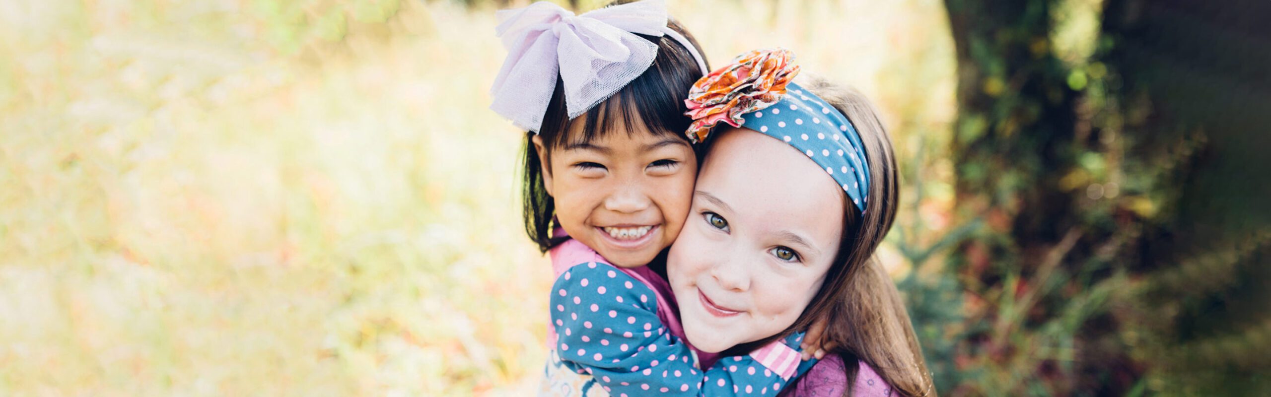 Girls hugging outside in a grassy field